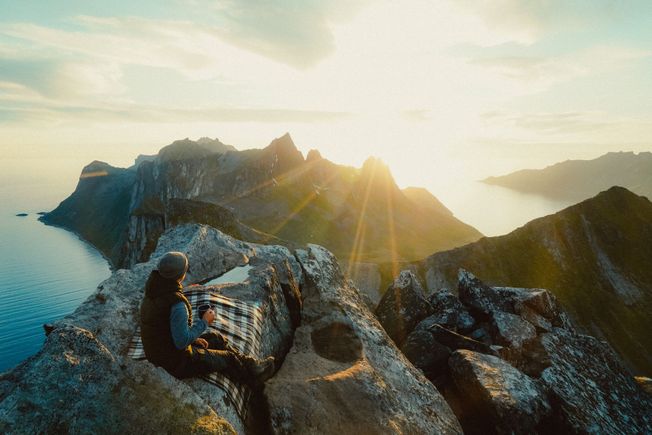 Person på toppen av fjell i solnedgang