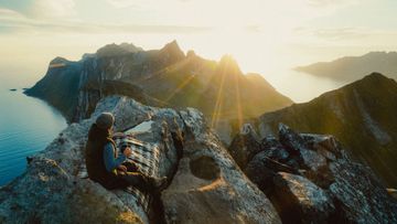 Person på toppen av fjell i solnedgang